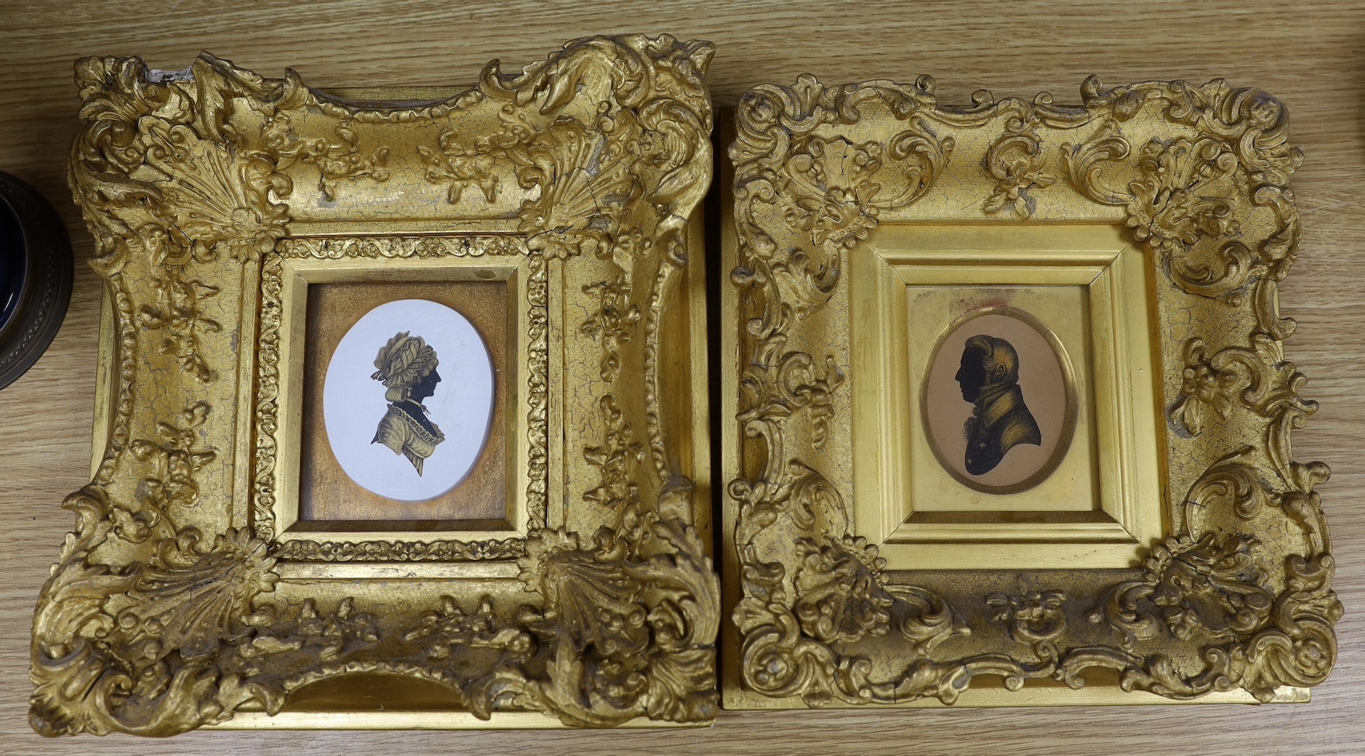Two early 19th century bronzed and cut paper silhouettes, housed in ornate gilt gesso frames
